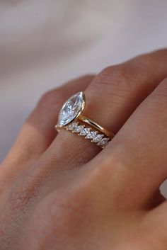 a woman's hand with a gold ring and diamond band on her left hand