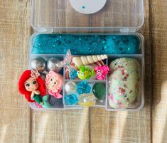 a plastic container filled with different types of toys and beads on top of a wooden table