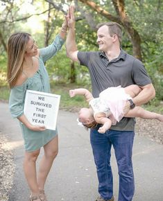 a man and woman holding a baby while standing next to a sign that says we survived the fire year