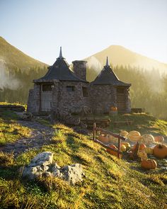 an old stone house with pumpkins in the foreground and mountains in the background