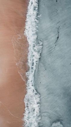 an aerial view of the ocean and beach with waves coming in from the water,