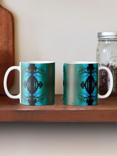 two coffee mugs sitting next to each other on a wooden shelf in front of a mason jar