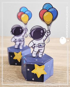 an astronaut is holding some balloons on top of a box with stars in the background