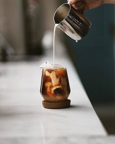 a person pouring liquid into a jar filled with food