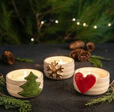 three candles with christmas decorations and pine cones