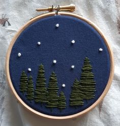 an embroidery project with trees and snow in the background