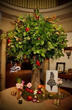 a small tree with lots of fruit on it in the middle of a room filled with candles