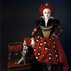 a woman in a red and black dress sitting on a chair