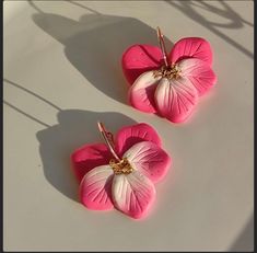 two pink and white flower shaped earrings sitting on top of a table