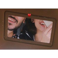 a man and woman are smiling in front of a photo frame with a heart on it