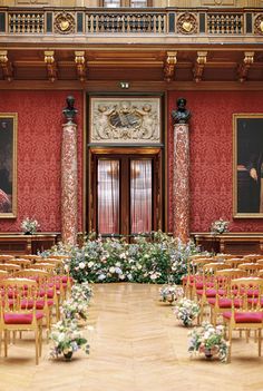 an ornately decorated room with red chairs and floral arrangements