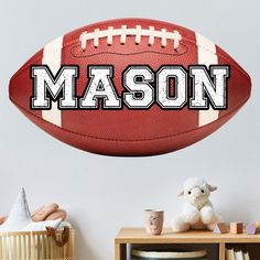 a football wall decal with the word mason on it and a stuffed animal next to it