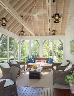 a covered porch with wicker furniture and large windows