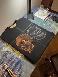 there is a t - shirt with a skull on it and two glasses next to it