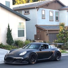 a black sports car parked in front of a house