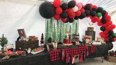 a table topped with red, black and white balloons next to a christmas themed cake