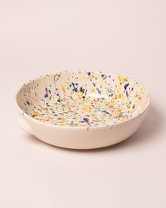 a white bowl with multicolored sprinkles on the rim and bottom