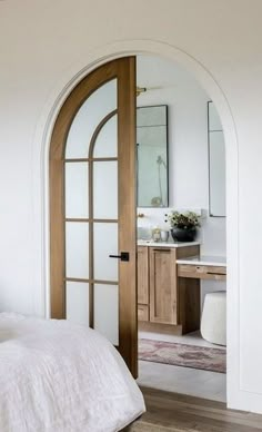 a bedroom with an arched doorway leading into the bathroom