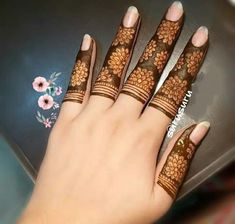 a woman's hand with henna tattoos on it and her fingers painted brown