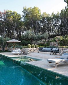 an outdoor swimming pool with lounge chairs and umbrellas