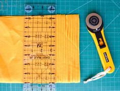 a pair of scissors sitting on top of a piece of yellow fabric next to a ruler