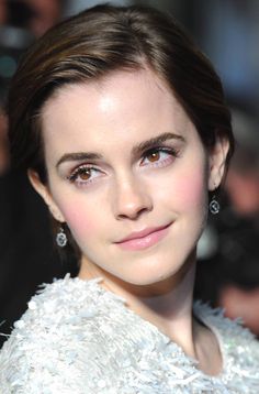 a close up of a person in a white dress with earrings on her head and eyes