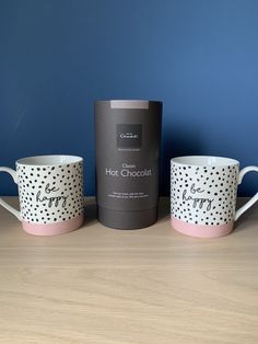 three coffee cups sitting next to each other on top of a wooden table in front of a blue wall