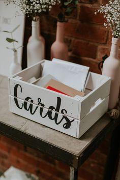 a wooden crate with the word cards on it sitting on a table next to vases and bottles