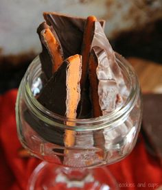 a glass jar filled with chocolate and orange candy bar pieces on top of a red napkin