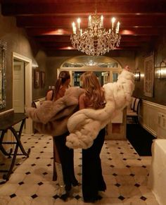 two women standing in a hallway with chandelier