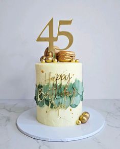 a white cake with gold decorations and the number 45 on top is sitting on a plate