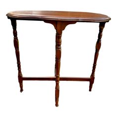 an oval wooden table with two legs and a shelf on one end, against a white background