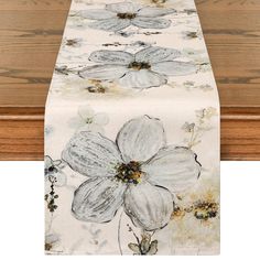 a table runner with white flowers on it and brown wood in the backround