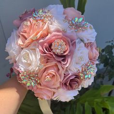 a bridal bouquet with brooches and flowers in the middle is being held by someone's hand