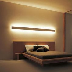 a large bed sitting in a bedroom next to a wall mounted mirror and light fixture