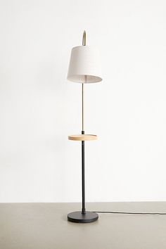 a table lamp with a white shade on it and a black stand next to it