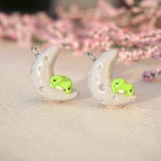 two small white and green earrings sitting next to each other on top of a table