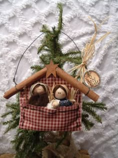 two dolls are sitting in a small house made out of wood and fabric, surrounded by greenery