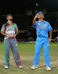 two men in blue and green uniforms standing next to each other on a baseball field