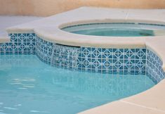 an outdoor hot tub with blue tiles on the sides and water running down it's side