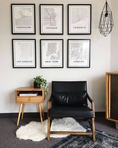 a living room with four framed maps on the wall and a black leather chair in front