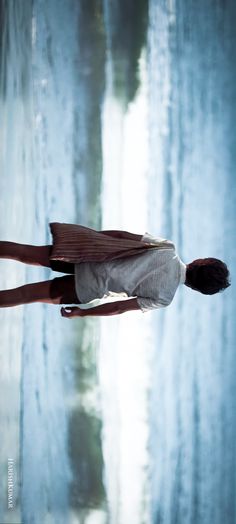 a woman standing in front of a body of water