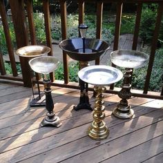 three candlesticks on a deck with one candle holder in the middle and two glass holders at the bottom