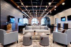 a living room with couches and chairs in it's center area, along with televisions on the wall