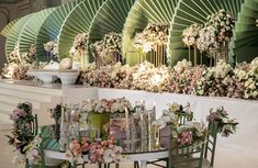 a table with flowers and candles on it in front of an elaborately decorated wall