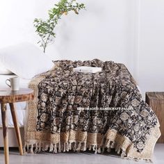 a black and white blanket sitting on top of a bed next to a wooden table