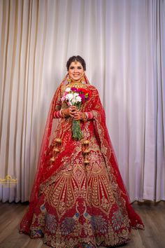 a woman in a red and gold bridal gown with flowers on her wedding day