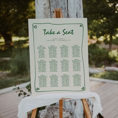 a wooden easel with a seating chart on it sitting in front of a tree