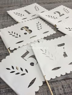 four white paper cutouts with leaves on them sitting on top of a wooden table