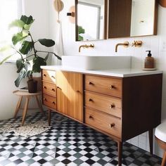 a bathroom with black and white checkered flooring, wooden cabinets and a plant in the corner